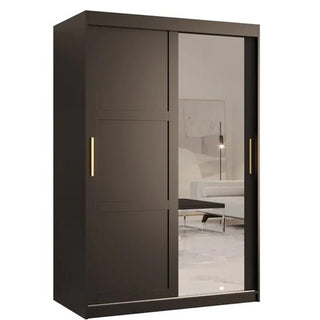 The Rieti II Mirrored Wardrobe with 2 sliding doors in black features gold vertical handles and includes one solid and one mirrored door, reflecting a white sofa and floor lamp in the room.