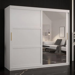 The Rieti II Mirrored Wardrobe 2 Sliding Doors 200cm in White, featuring gold handles and a mirrored door, stands against a black grooved wall and reflects a stylish living room with a sofa and framed artwork.