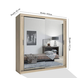 The CHICAGO II 2 Door Mirrored Oak Wardrobe (203cm wide, 217cm high, 62cm deep) features modern sliding mirrored doors that reflect bedroom decor, offering stylish and spacious storage for your room.