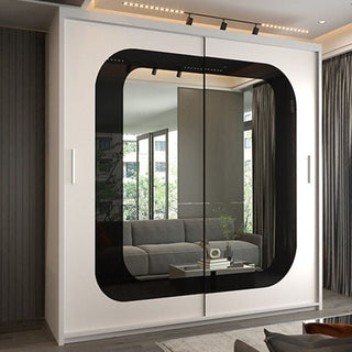 The COVINA 2 Door Mirrored Wardrobe (150cm) in white with a black strip features large, rounded square mirrored doors that reflect a stylish living room with gray sofa, windows, greenery, ceiling lights, and curtains for a modern touch.