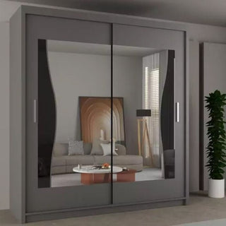 The HEFFNER 2 Door Mirrored 180cm Grey Sliding Wardrobe reflects a living room with sofa, cushions, round coffee table, framed art, lamp, and window blinds. A tall plant stands to the right of this stylish bedroom storage solution.