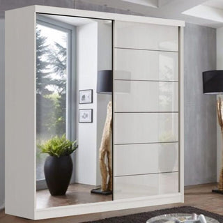 The CHOICEWARDROBE Infinite 2 Door Sliding Mirrored Wardrobe, 150cm wide with a modern white finish, stands in a stylish room with a large window, black floor lamp, potted plant, and wooden decorative accents.