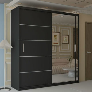 The KEYNES 2 Door Mirrored Wardrobe in black (150cm) stands in a modern living room with decorative wall panels, a beige sofa, framed art, and a floor lamp.