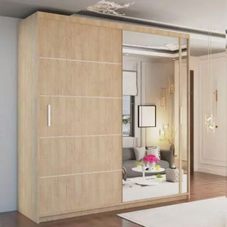 The KEYNES 2 Door Mirrored Wardrobe Oak (150cm) stands in a modern room, featuring one wood panel door and one full-length mirror that reflects a sofa, table, and décor. Spacious shelving is inside for organized storage.