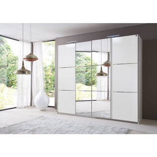 A contemporary bedroom with the LANDSCAPE 4 Door Mirrored Wardrobe in white (350cm), a gray rug, pendant lights, and floor-to-ceiling windows showcasing lush greenery outside.