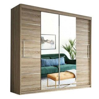 The LISBANE 2 Door Mirrored Wardrobe Oak (150cm) features full-length mirrored doors that reflect a green sofa, orange ottoman, plant, and wall art, blending stylish design with practical bedroom storage in your living room.