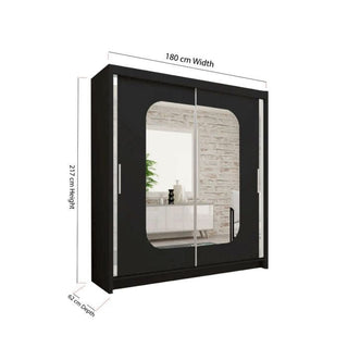 The MERICA 2 Door Mirrored Sliding Wardrobe in black offers spacious bedroom storage with stylish mirrored doors. Dimensions: 180cm wide, 217cm high, and 62cm deep, reflecting a modern room with shelves and décor.