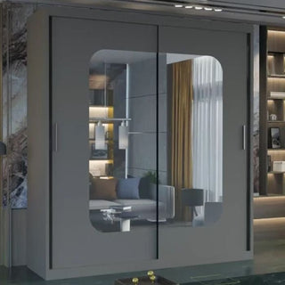 The MERICA 2 Door Mirrored Wardrobe Grey (120cm) features sliding glass doors and a modern design, reflecting a stylish room with a sofa, yellow curtains, and shelves—ideal elegant storage for any bedroom.