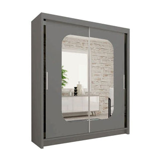 The MERICA 2 Door Mirrored Sliding Wardrobe in grey (180cm) adds modern style and sleek bedroom storage, reflecting decor like a white console table, decorative items, a plant, and a white brick wall.