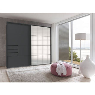 A modern room features a SOGO 2 Door Mirrored Wardrobe in graphite (225cm), a pink round pouf, white floor lamp, light rug, and floor-to-ceiling windows with views of water and greenery.