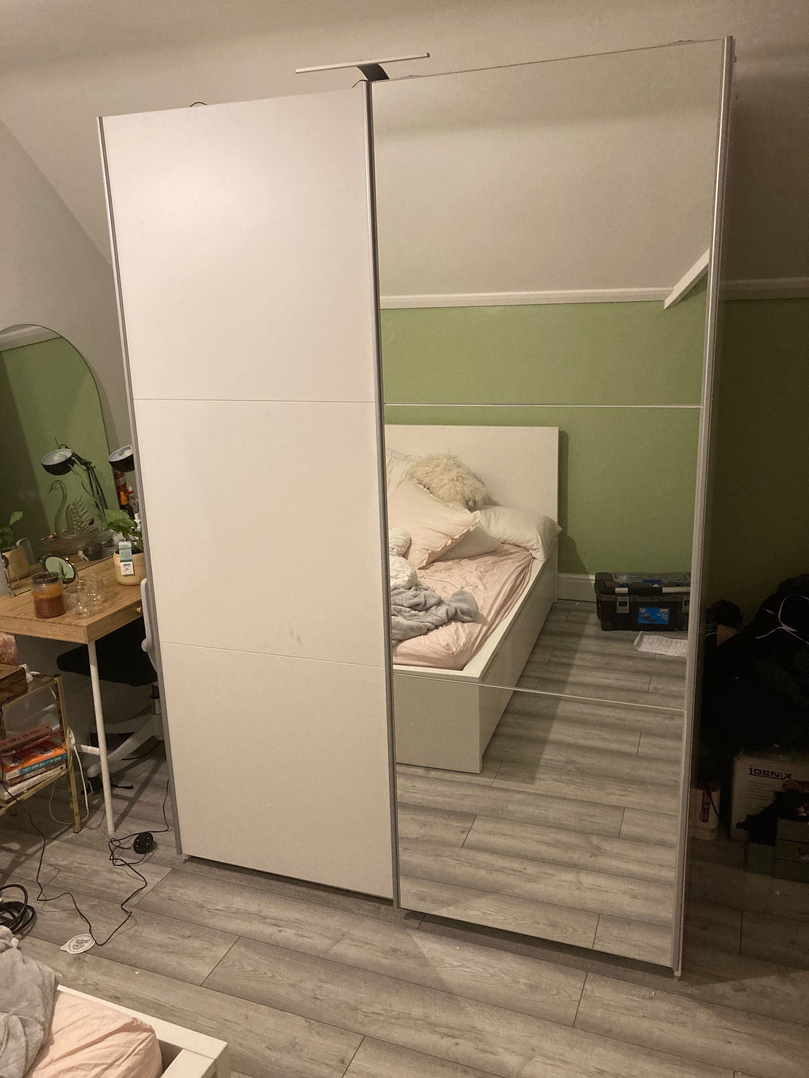 White 2-door mirrored sliding wardrobe reflecting an unmade bed and bedroom interior.