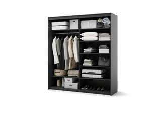 Black sliding wardrobe interior with clothes on hanging rail and shelves stocked with bedding and storage boxes.