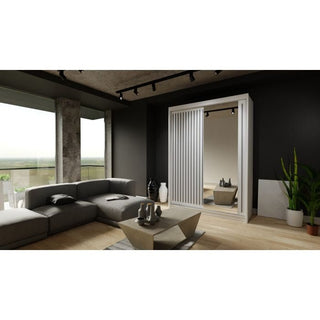 A modern living room with a gray sectional sofa, geometric coffee table, large windows, wood floors, potted plants, and track lighting. A ZEUS 2 Door Mirrored Sliding Wardrobe in white (150cm) adds style and storage to the space.