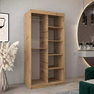 The Tavira I Mirrored Wardrobe with 2 sliding doors (100cm, Artisan Oak) features dual sections—one with two hanging rods and another with five shelves—perfect for modern spaces with decor, ribbed walls, and a round mirror.