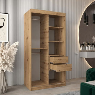The Tavira I Mirrored Wardrobe with 2 sliding doors in artisan oak (100cm) features shelves, hanging rails, and drawers, and stands in a modern room with striped walls, a decorative mirror, and pampas grass in a vase.