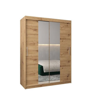 The Tavira I Mirrored Wardrobe features 2 sliding doors with full-length mirrors and metal handles in a natural artisan oak finish, reflecting the bed and part of the bedroom for a spacious, stylish look.