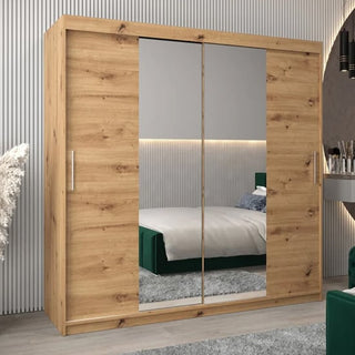 The Tavira I Mirrored Wardrobe with 2 sliding doors in Artisan Oak (200cm) stands in a modern bedroom, its finish complementing the green upholstered headboard and neutral decor.