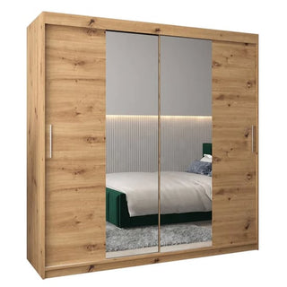 The Tavira I Mirrored Wardrobe 2 Sliding Doors 200cm in Artisan Oak is featured in a modern bedroom with a green bed, gray carpet, and ribbed wall paneling.