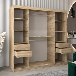 The Tavira I Mirrored Wardrobe with 2 sliding doors in Sonoma Oak (200cm) is displayed in a modern room featuring a ribbed wall, round mirror, and part of a green chair.
