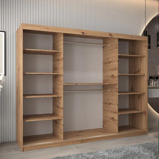 The Tavira I Mirrored Wardrobe with 3 sliding doors (250cm) in artisan oak stands against a vertically grooved wall, featuring multiple shelves, two hanging rods, and a light brown natural wood finish.