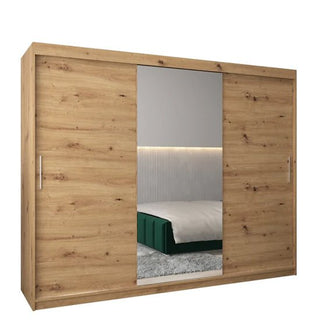 The Tavira I Mirrored Wardrobe in artisan oak features three sliding doors, a central mirrored panel, and complements modern bedrooms with vertical wall paneling and LED strip lighting.