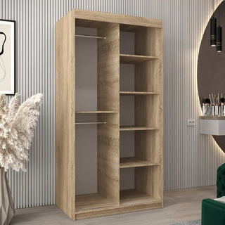 The Tavira II Mirrored Wardrobe with 2 sliding doors in Sonoma Oak features two hanging rods on the left and six open shelves on the right, complementing a modern room with a slatted wall, pampas grass, and a round mirror.