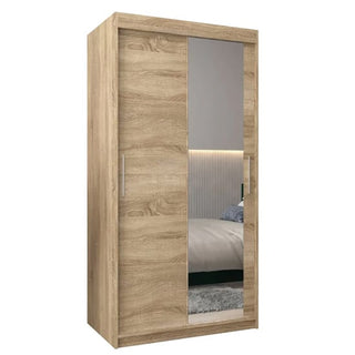 The Tavira II Mirrored Wardrobe in Sonoma Oak features two sliding doors, sleek vertical metal handles, a full-length mirror on one door, and a light wood finish—offering both style and functionality at 100cm wide.