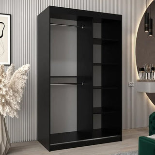 The Tavira II Mirrored Wardrobe 2 Sliding Doors 120cm in Black, featuring two left hanging rods and four right shelves, stands in a modern room with a striped wall, plants, framed art, and a vanity table.