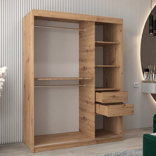 The Tavira II Mirrored Wardrobe with 2 sliding doors (150cm, Artisan Oak) stands against a striped wall near a circular mirror and vanity table. It features left-side hanging sections, right-side shelves, and two open drawers.