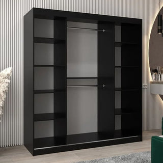 The Tavira II Mirrored Wardrobe with 2 sliding doors in black (180cm), featuring multiple side shelves and two central hanging rods, stands against a vertically striped wall in a modern room.