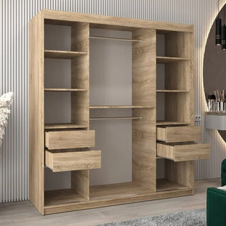 The Tavira II Mirrored Wardrobe with 2 sliding doors (180cm) in Sonoma Oak features multiple shelves, two hanging rods, and four drawers—two on each side. It stands on a light-colored floor against a wall with vertical paneling.