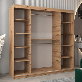 The Tavira II Mirrored Wardrobe with 2 sliding doors in Artisan Oak stands against a modern striped wall, featuring shelves on both sides and two central hanging rods to complement the room’s contemporary style.