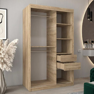 The Tavira III Mirrored Wardrobe with 2 sliding doors (120cm) in Sonoma Oak stands against a vertically grooved wall, with decorative items and a framed picture placed nearby.