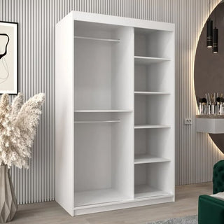 The Tavira III Mirrored Wardrobe, 120cm wide in white, features two sliding doors. The left section has two hanging rods; the right side provides five open shelves. Perfect for modern rooms with decorative plants and a circular mirror.