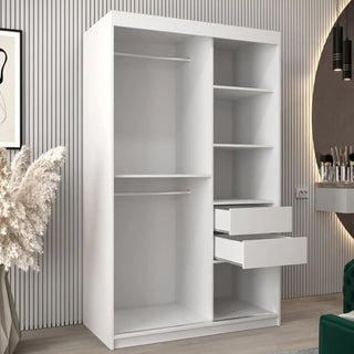 The Tavira III Mirrored Wardrobe, 120cm in white with two sliding doors, two hanging rods, four shelves, and two open drawers stands in a modern room with light wood flooring and a green chair.