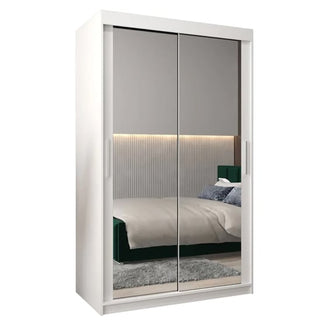 The Tavira III Mirrored Wardrobe 2 Sliding Doors 120cm in White reflects a modern bedroom with a bed, gray accent wall, illuminated headboard, and rug.