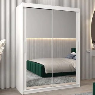 The Tavira III Mirrored Wardrobe with 2 sliding doors (150cm, white) features large mirrored panels reflecting a green upholstered bed, gray rug, and modern bedroom decor.