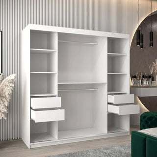 The Tavira Wooden Wardrobe 2 Sliding Doors 200cm In White features four shelves, four drawers, and two hanging rods. It’s shown against a striped wall in a modern room with a rug, green chair, and vanity table.