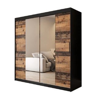 The Topeka 2 Mirrored 200cm Wardrobe features a black frame, rustic dark oak panels, and two central mirrored sliding doors that reflect a white sofa with cushions in a neutral-toned room.