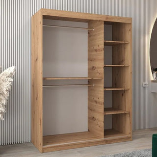 The Vevey I Wooden Wardrobe with 2 sliding doors (150cm, Artisan Oak) features dual open hanging sections on the left and five shelves on the right, shown in a modern room with light walls and a decorative corner plant.