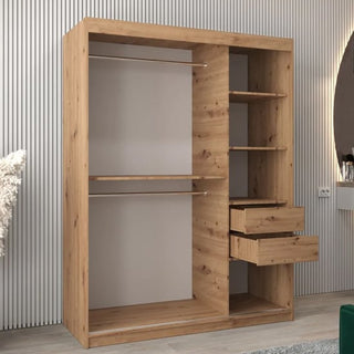 The Vevey I Wooden Wardrobe, 150cm in artisan oak, features 2 sliding doors, left-side hanging rods, right-side shelves and drawers, and stands against a vertically grooved wall to showcase its elegant craftsmanship.