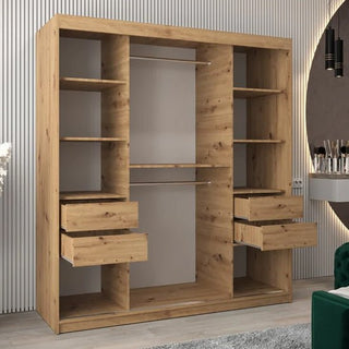The Vevey I Wooden Wardrobe with 2 sliding doors (180cm, artisan oak) stands against a light striped wall in a modern room, featuring multiple shelves, four open drawers, and two hanging rods behind its sleek façade.