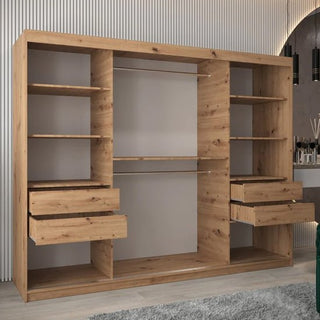 The Vevey I Wooden Wardrobe (250cm, 3 sliding doors) in artisan oak features multiple shelves, four drawers, hanging rods, and compartments, and stands in a modern room with a gray rug and stylish décor accents.