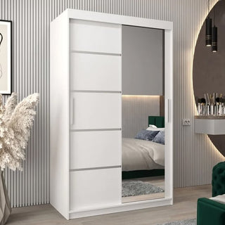 A Vevey II Mirrored Wardrobe 2 Sliding Doors 120cm in White stands in a modern bedroom with striped walls, pampas grass decor, and its large mirror reflects the bed and bedside table.