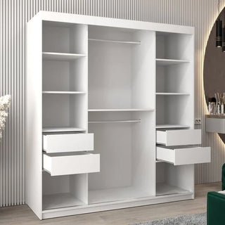 The Vevey II Mirrored Wardrobe features 2 sliding doors, a white finish, multiple shelves, 2 hanging rods, and 4 open drawers. It stands against a vertically lined wall beside a mirror and a small table with various items.