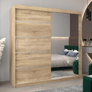 The Vevey II Mirrored Wardrobe 2 Sliding Doors 200cm in Sonoma Oak, with a full-length mirror, is showcased in a modern bedroom featuring a bed with green headboard, wall lighting, and a dressing table.