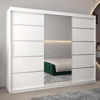 The Vevey II Mirrored Wardrobe 3 Sliding Doors 250cm in White features a full-length mirror and stands in a modern bedroom with vertical wall paneling, with the bed reflected in its spacious mirrored doors.