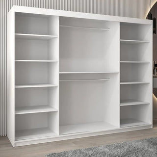 The Vevey II Mirrored Wardrobe with 3 sliding doors (250cm, white) features multiple shelves and 2 hanging rods, standing on a wooden floor with a gray rug and vertical striped wall paneling in a modern room.