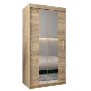The Vevey III Mirrored Wardrobe features 2 sliding doors in Sonoma Oak, with central mirrors reflecting a bed, headboard, and a wall with vertical lines.