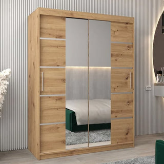 The Vevey III Mirrored Wardrobe 2 Sliding Doors 150cm in Artisan Oak, featuring center mirrors and silver accents, stands in a modern bedroom with vertical wall paneling, its doors reflecting the bed.